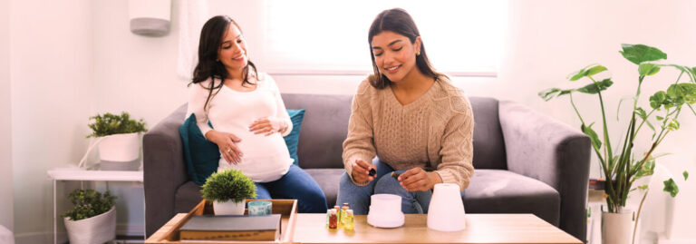 Two women in a cozy living room, one pregnant, engaged in conversation.