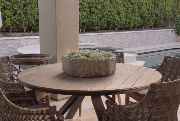 Outdoor dining table with chairs and a decorative plant centerpiece.