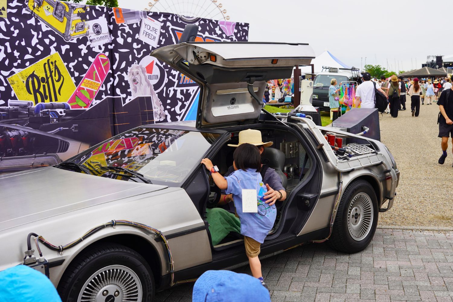 Children interacting with a DeLorean car at an outdoor event.