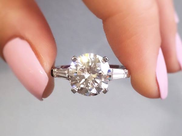 person holding a round diamond rinng