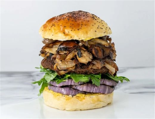A stacked burger with pulled meat, lettuce, and purple onion on a bun.