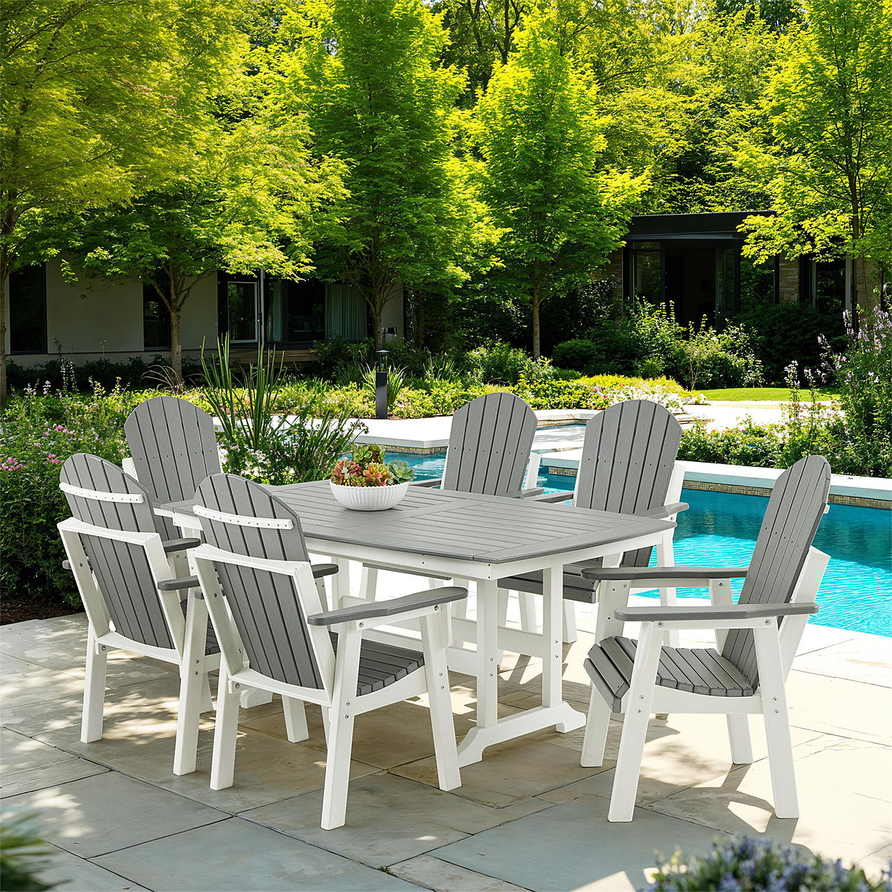 Outdoor dining set near a pool, surrounded by green trees and plants.
