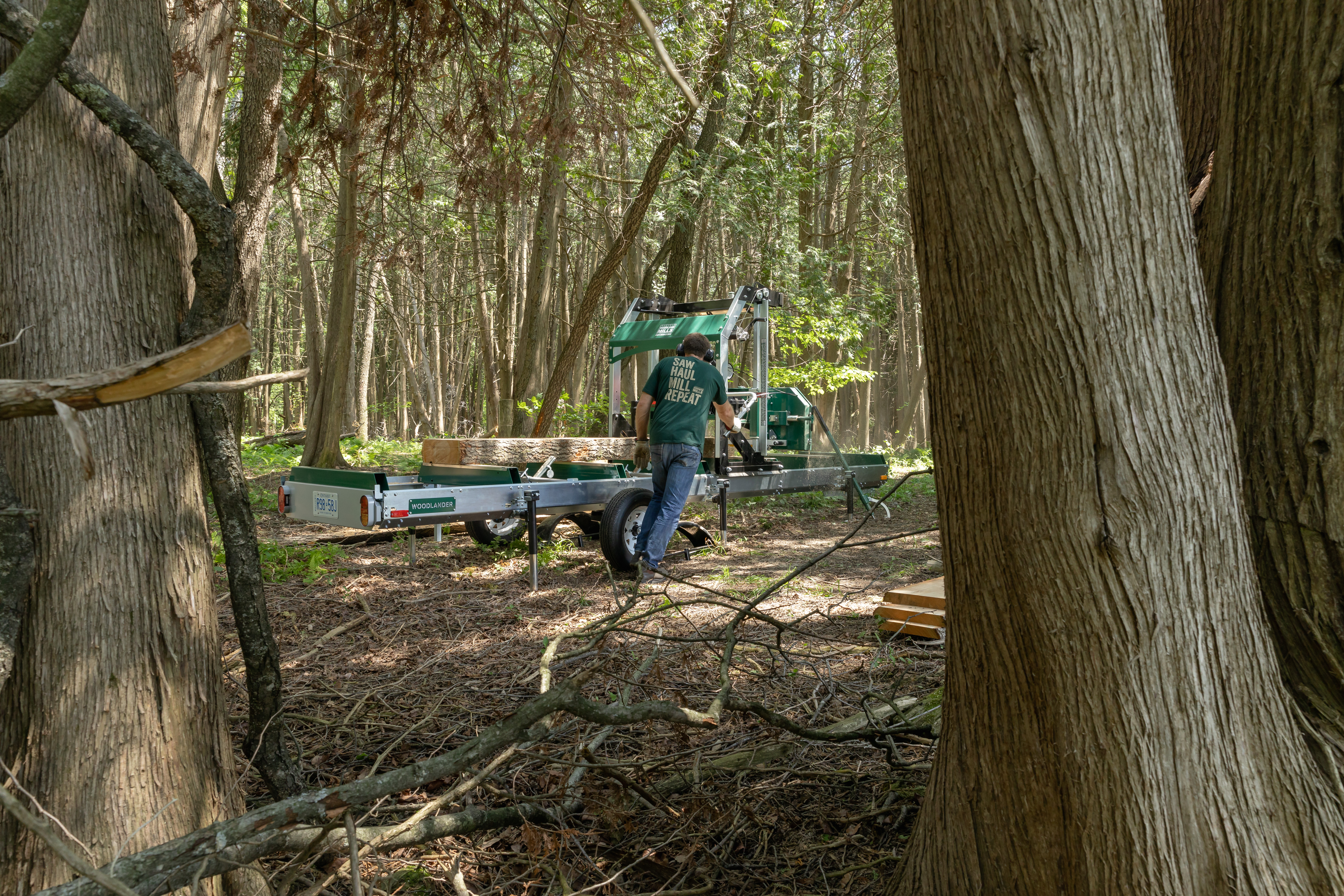 A Woodland Mills portable sawmill amidst trees in a forest setting.