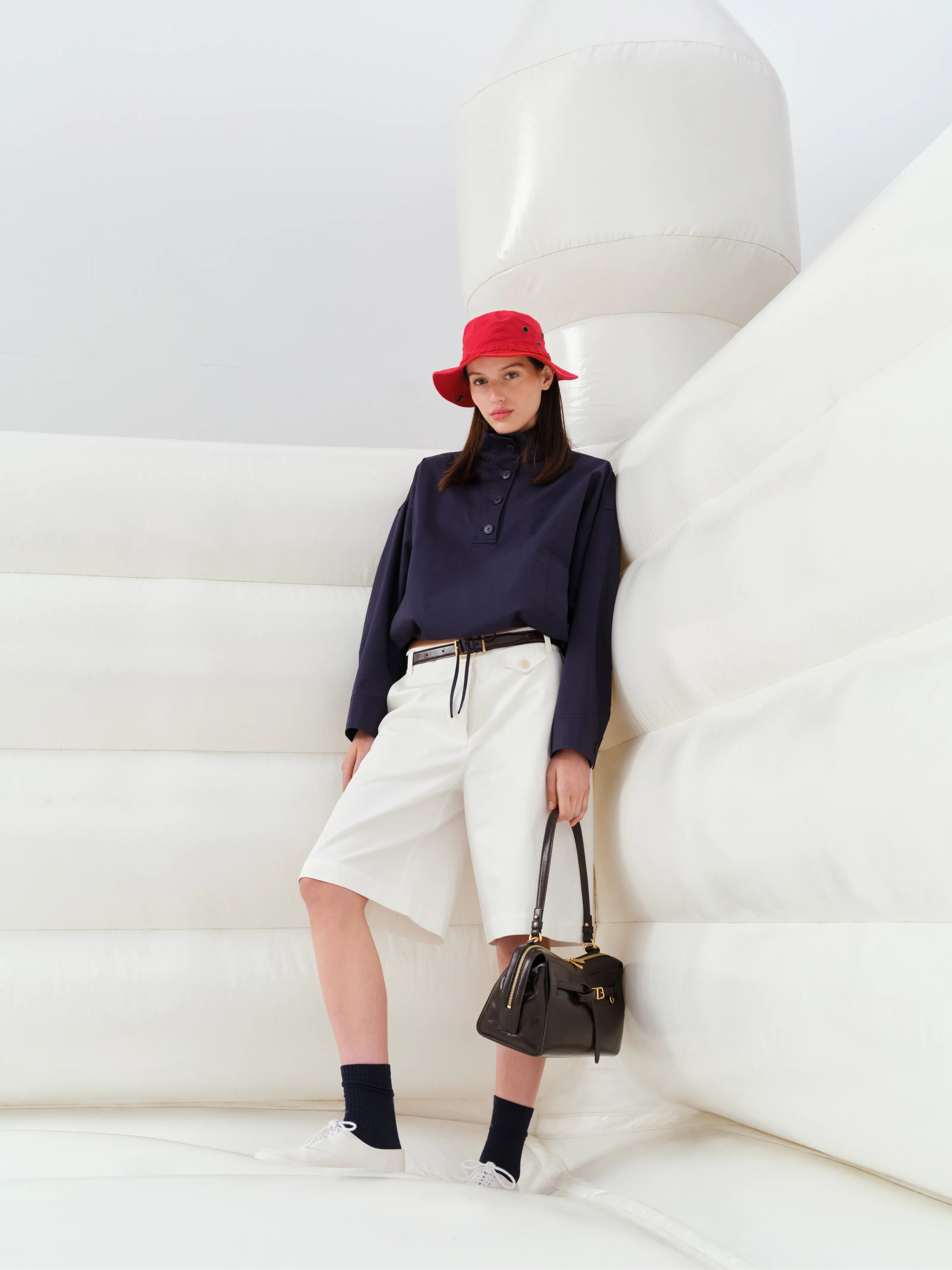 Person in a red hat and stylish outfit posing against a white background.