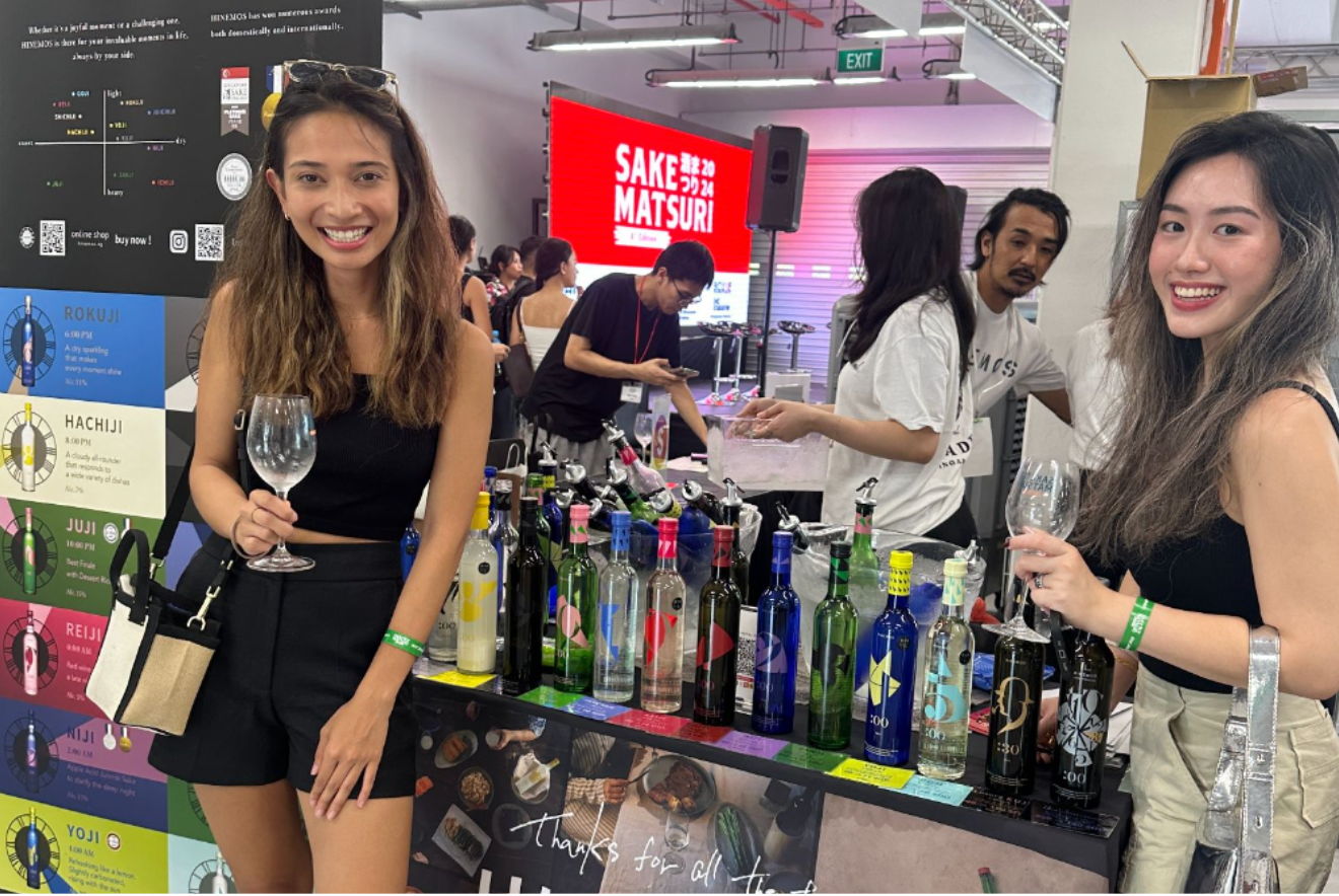 Two women holding glasses at a bar with various drink bottles.