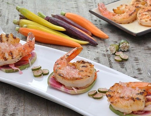 Grilled shrimp served on a platter with colorful vegetables.