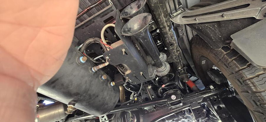 Close-up undercarriage view four black train horn trumpets air tank compressor and wiring Stealth Spare Tire Delete on Dirk's 2026 Toyota Tundra gallery photo 3