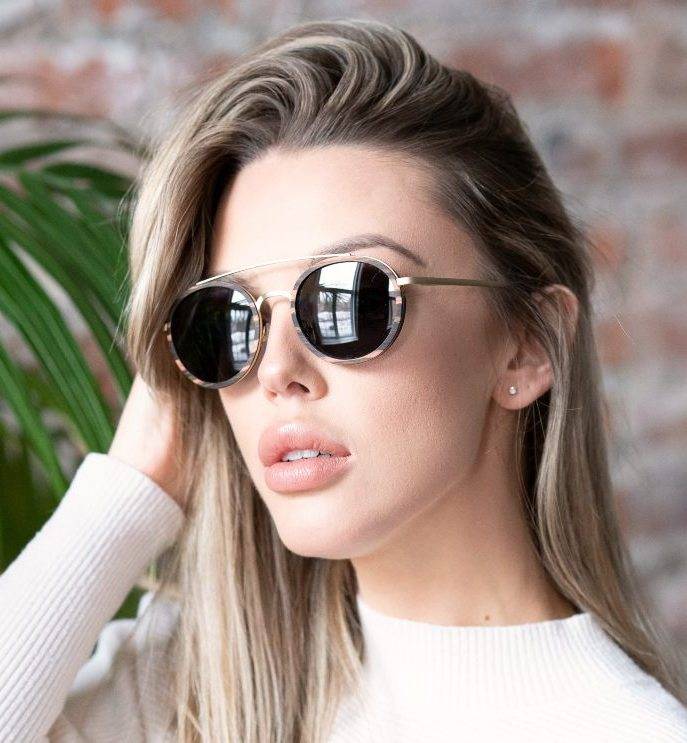 Woman wearing Aspen Gold, Gold Round High End Sunglasses with a white shirt