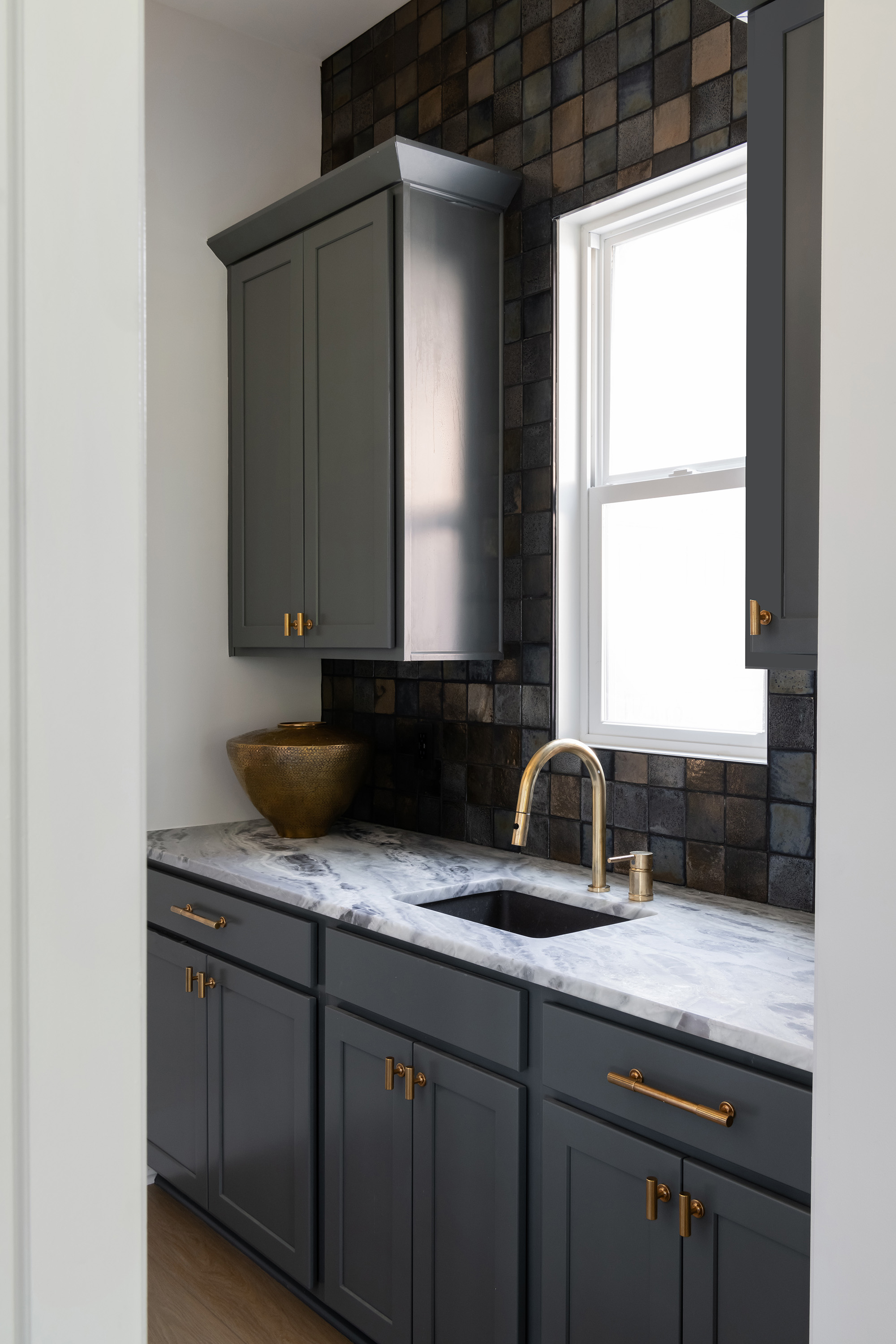 Navy kitchen design by Victoria Forehan, finished with brass handles and accessories and tiled wall