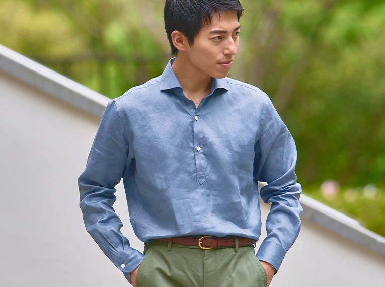 A man in a blue shirt and green pants standing outdoors.