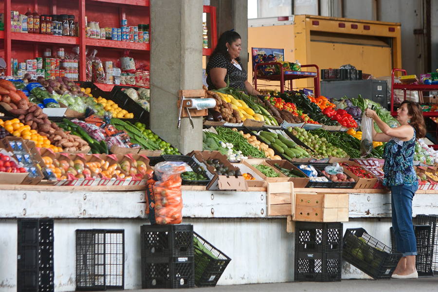 woman holding up produce bag  at a market stall