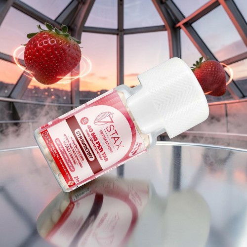 A bottle of strawberry-flavored product with strawberries in the background.
