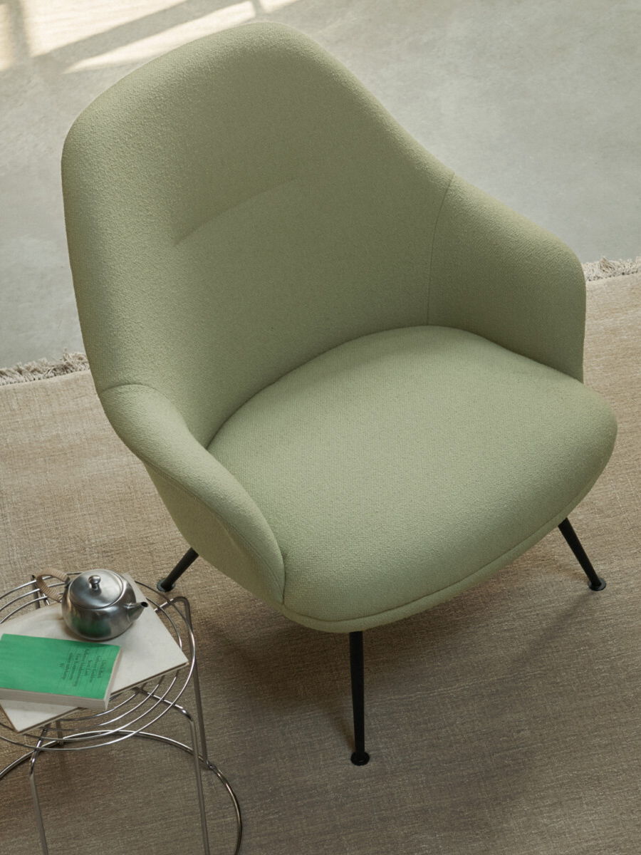 A light green &tradition chair next to a small table with a teacup.