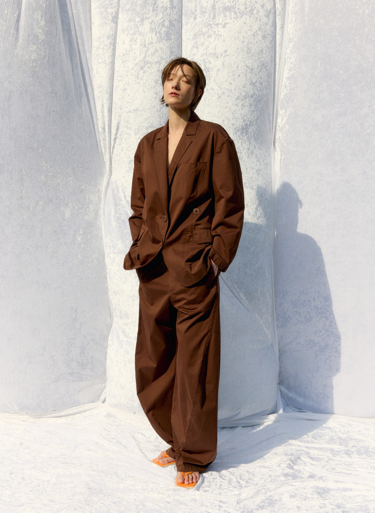 Person in a brown suit posing against a light backdrop.