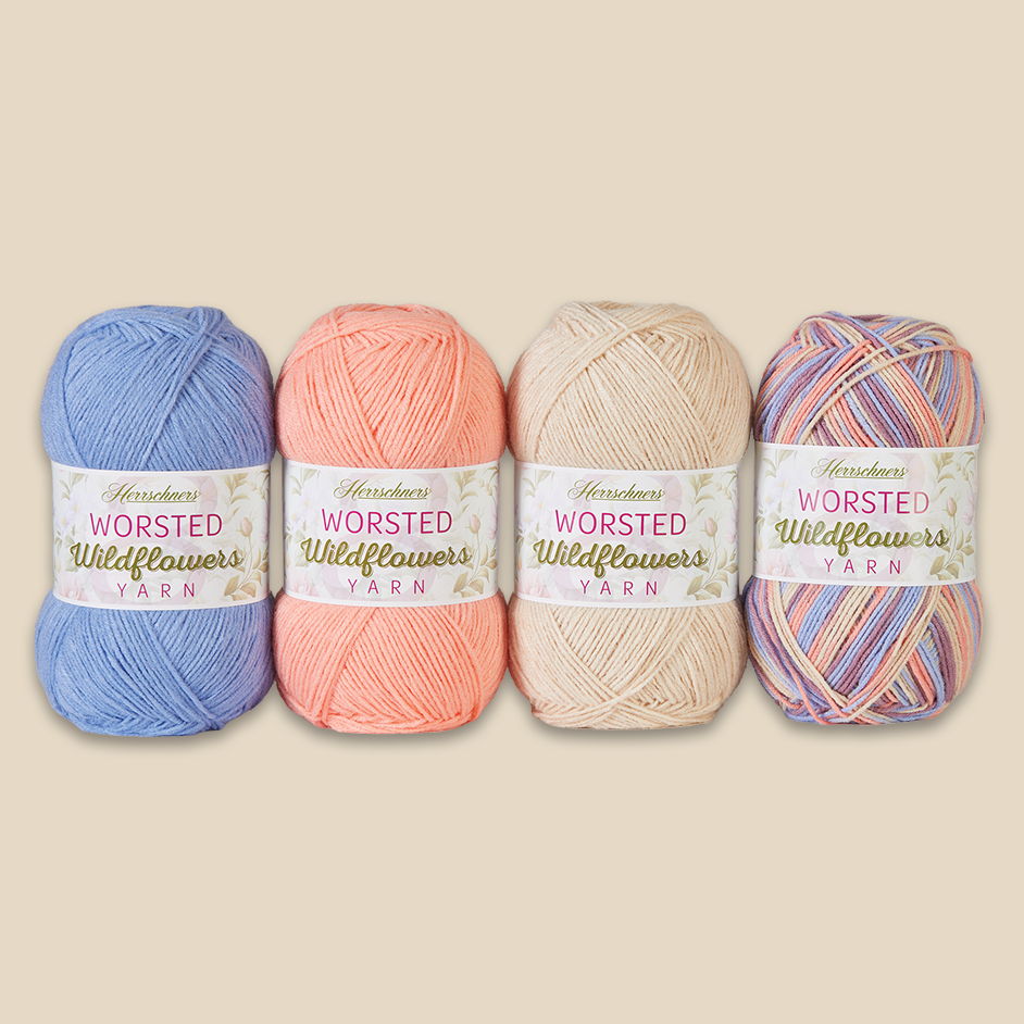 Four skeins of Herrschners Worsted Wildflowers yarn in various colors on a neutral background.