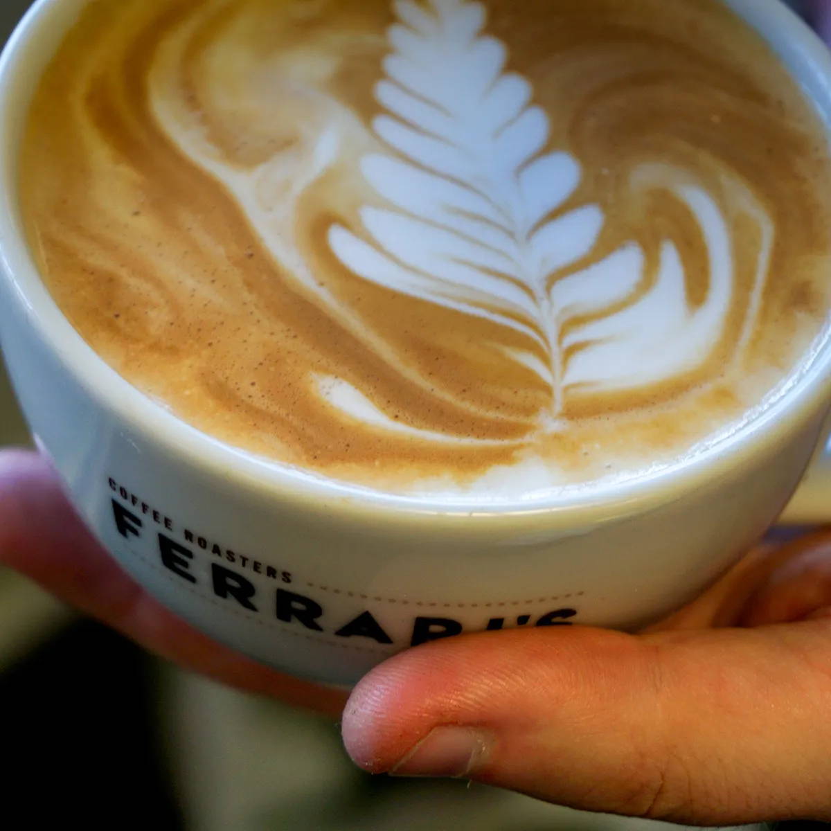 Ferrari's Coffee, a hand-holding Ferrari's Cup with latte art
