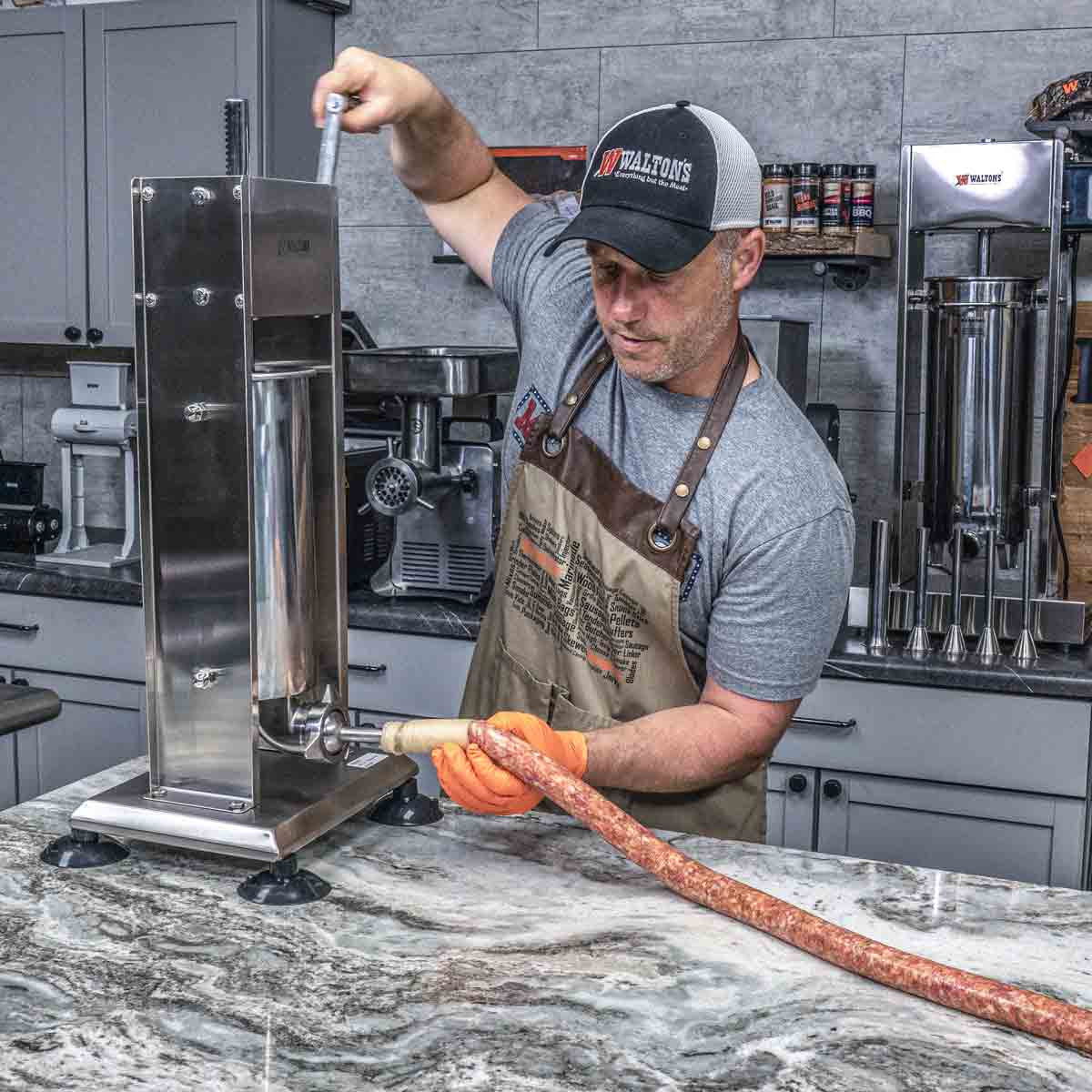 Person using a sausage stuffer in a kitchen setting.