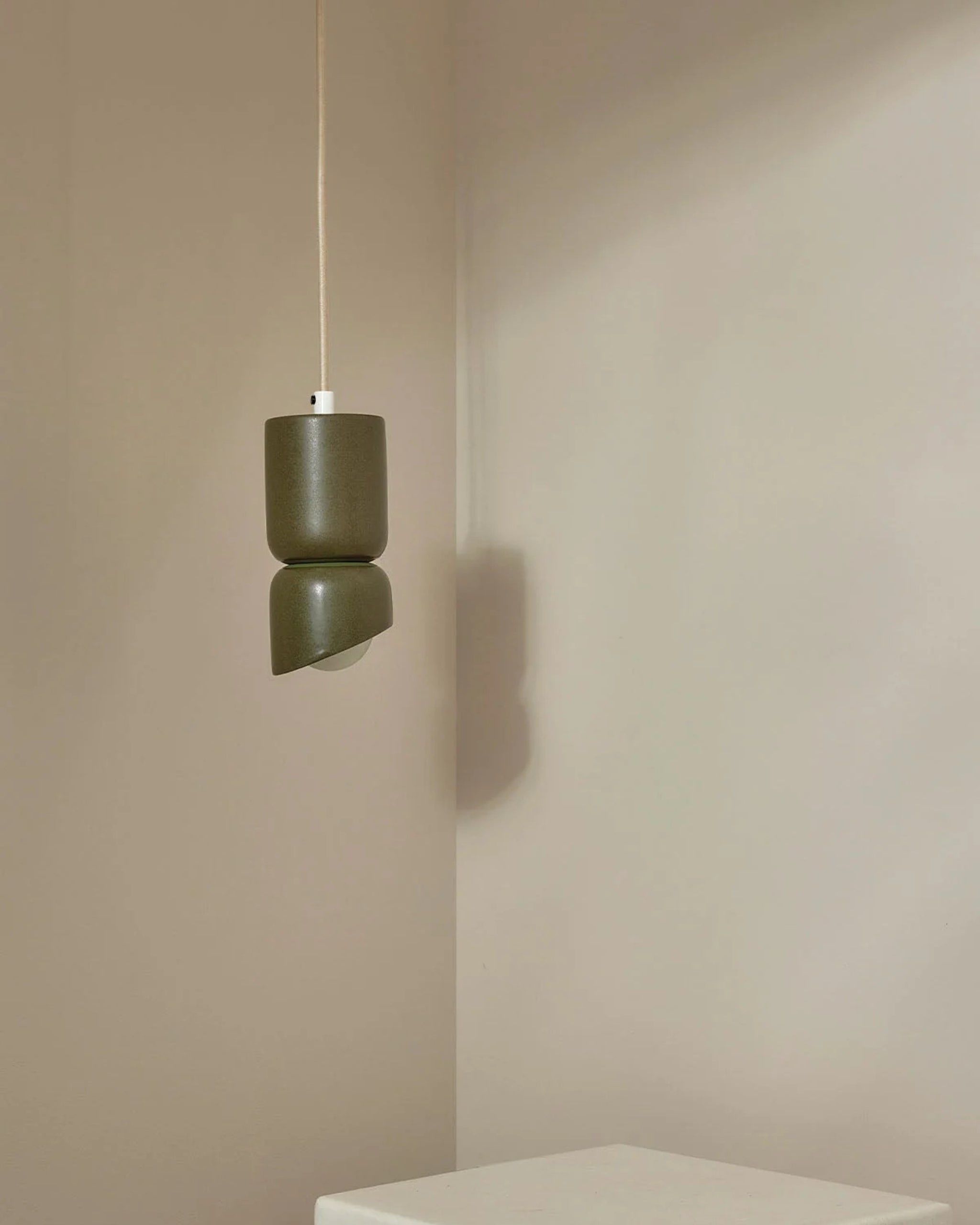 Green pendant light hanging against a beige wall