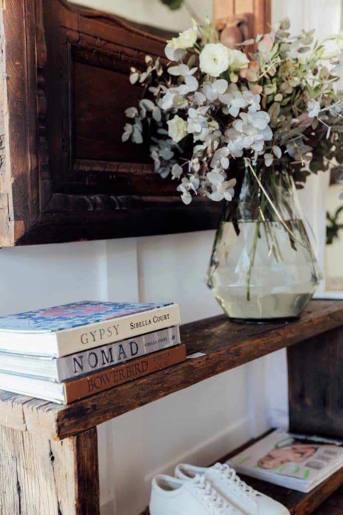 Green flowers in a glass vase on thick wooden entry table