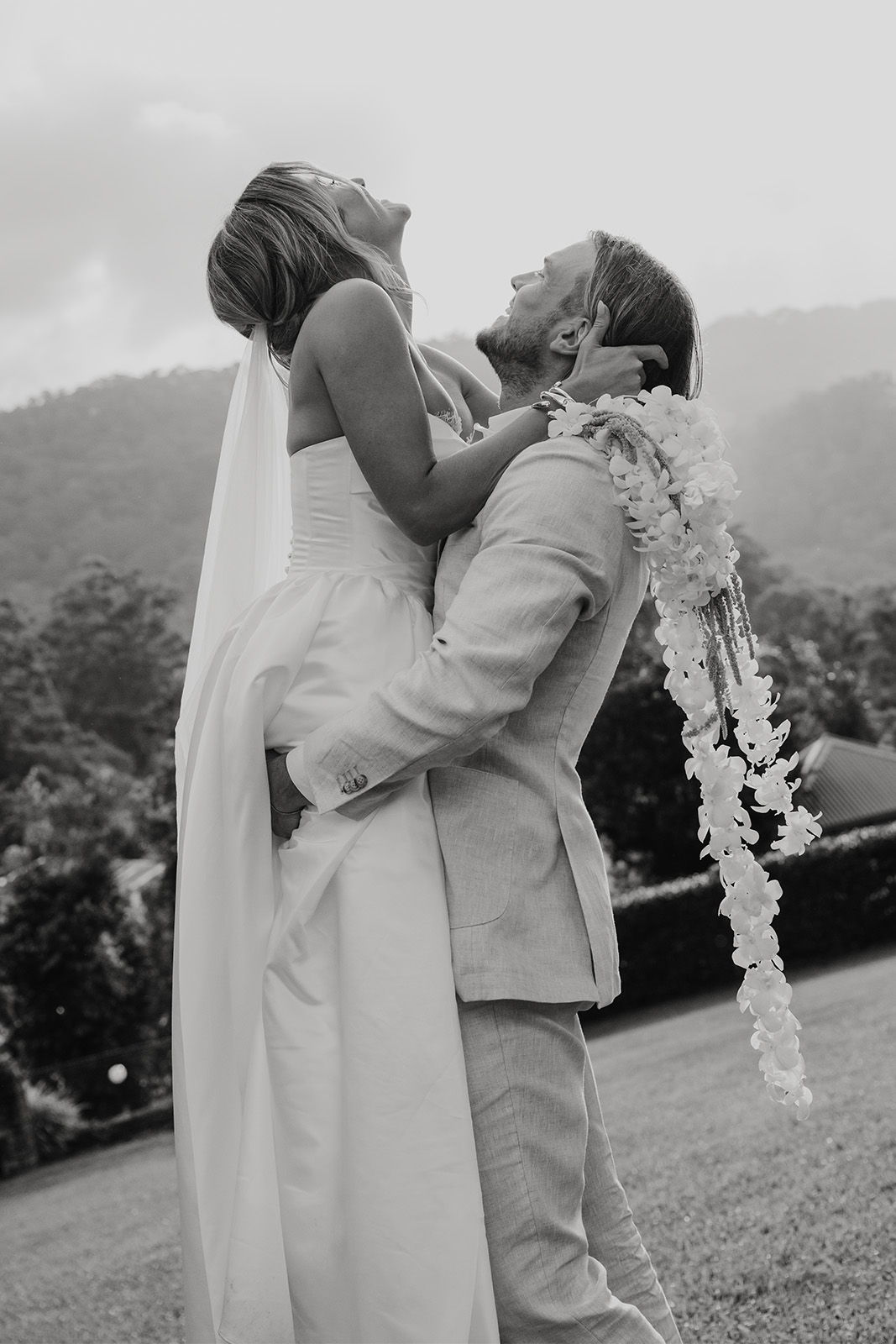 Bride and groom joyfully celebrating outdoors in black and white.