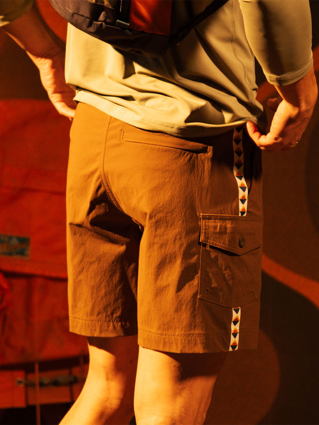 Person wearing brown shorts, facing away, with a backpack.