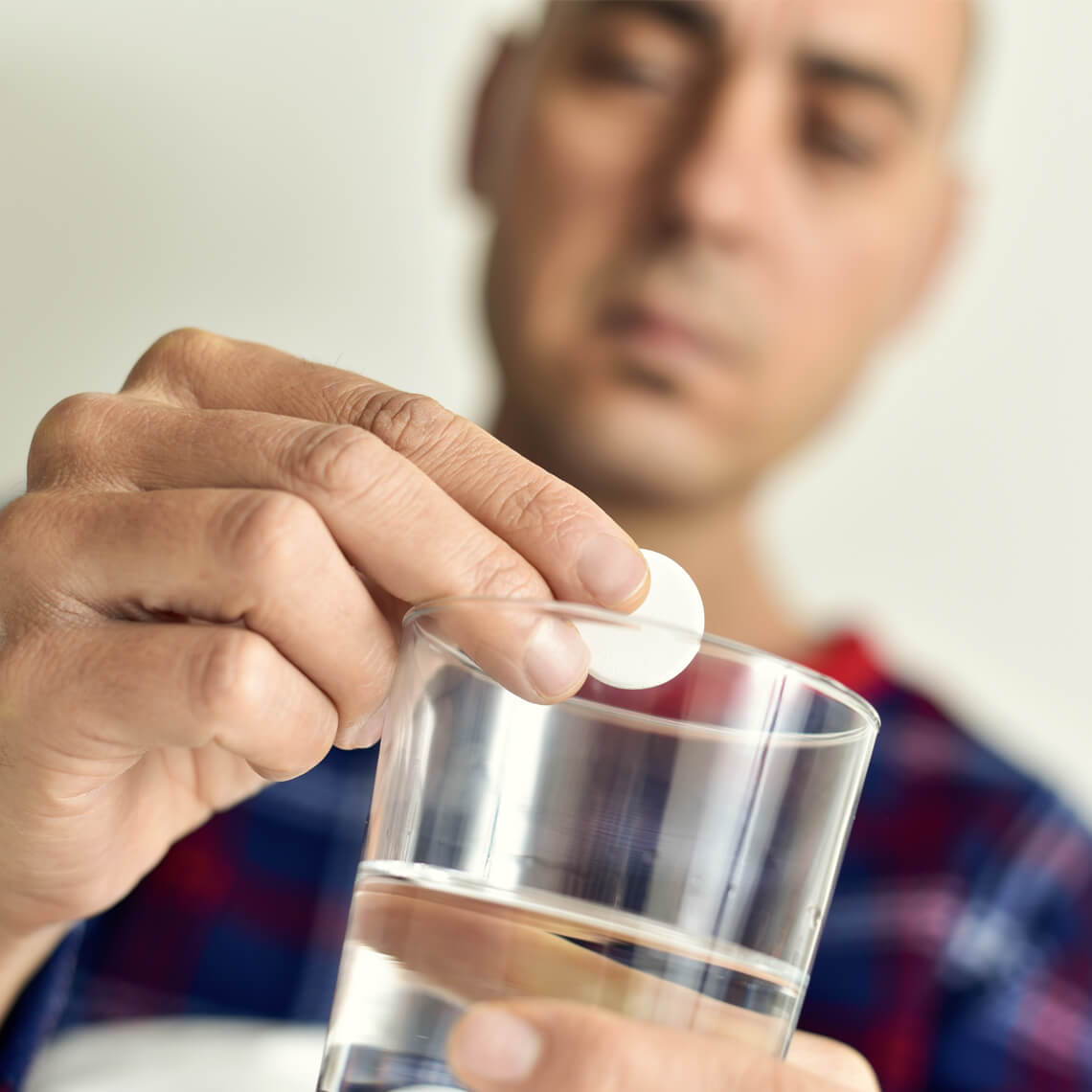 Man adding a tablet to a glass of water.