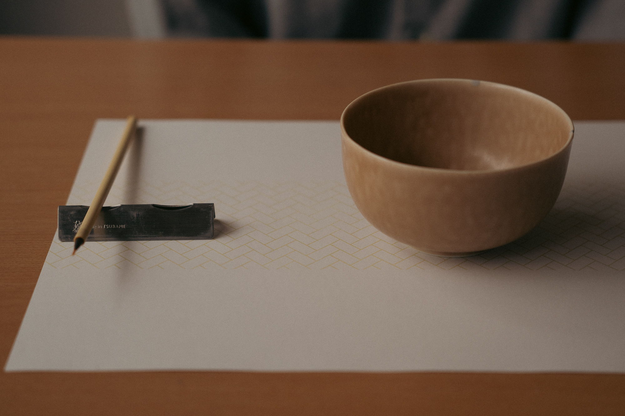 A wooden bowl and chopsticks on a white paper mat.