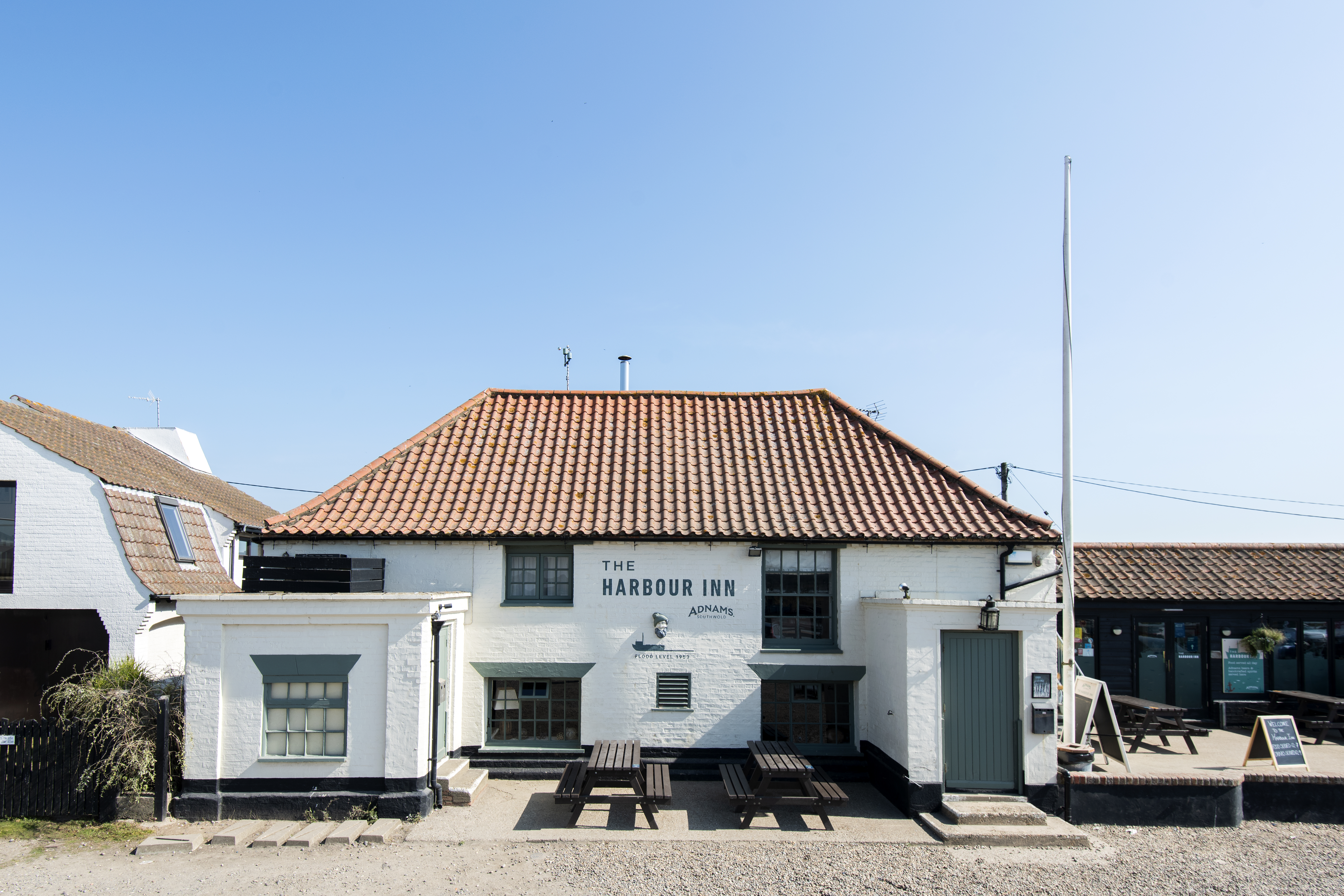 White building with a red roof, outdoor seating, and clear blue sky.
