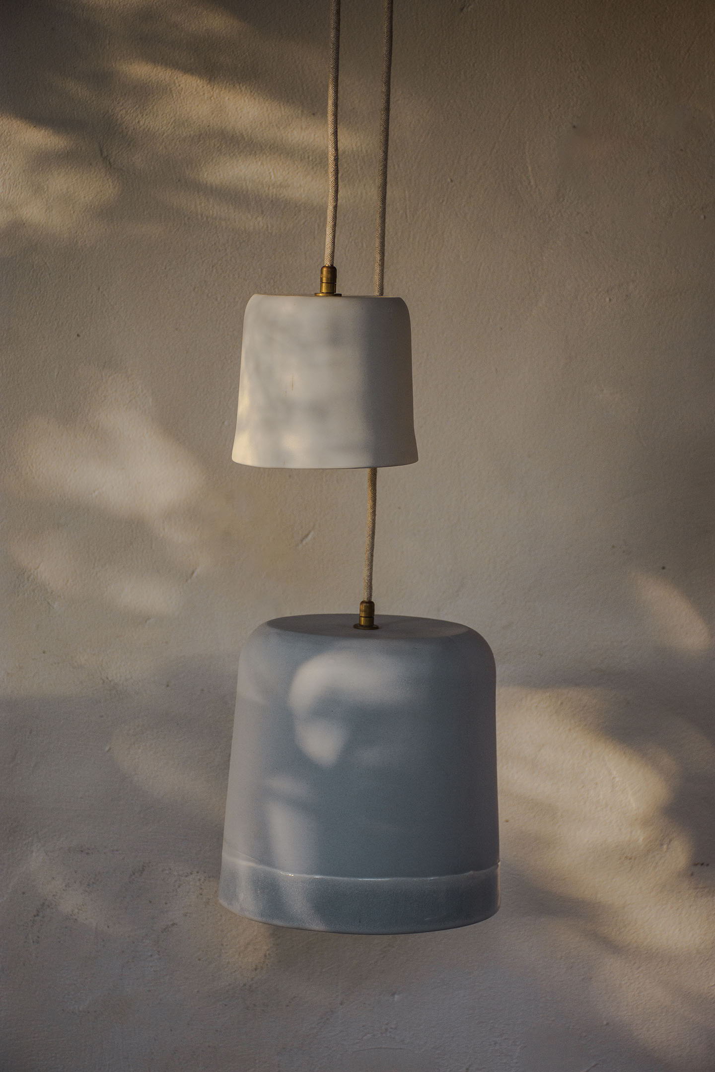 Two pendant lamps hanging against a textured, neutral background.