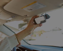 A close-up of a hand holding rear view mirror against a blurred background.