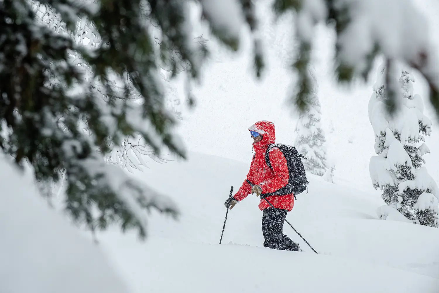 Person splitboarding in deep snow, surrounded by trees in a snowy landscape.