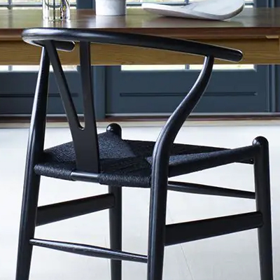 Black wooden chair beside a table in a bright room.