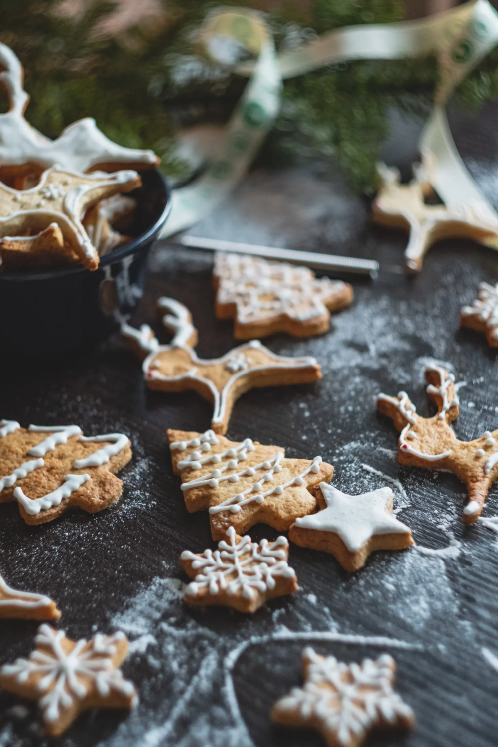 Iced and decorated gingerbread cookies on a countered dusted with flour.
