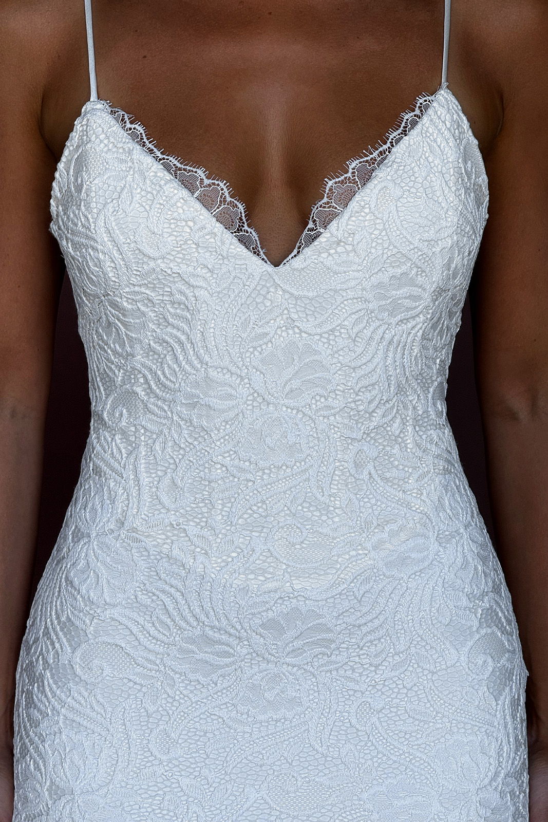 White lace dress with a deep V-neck and spaghetti straps.