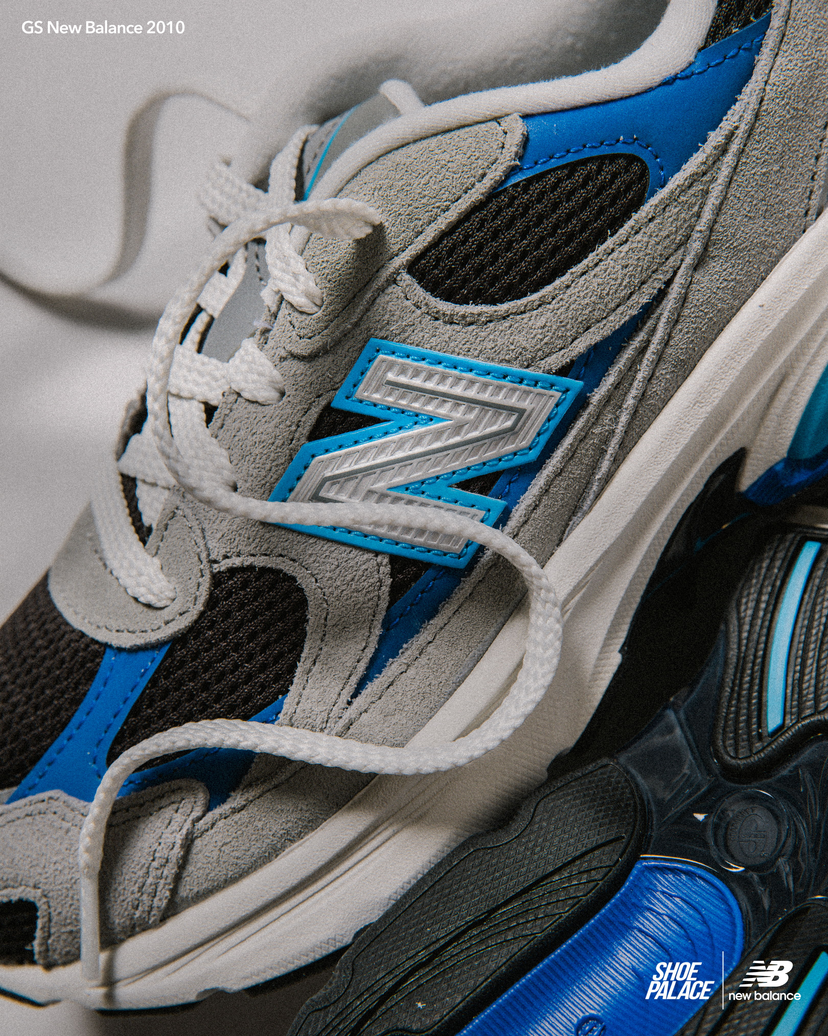 Gray and blue New Balance sneakers with laces on a neutral background.