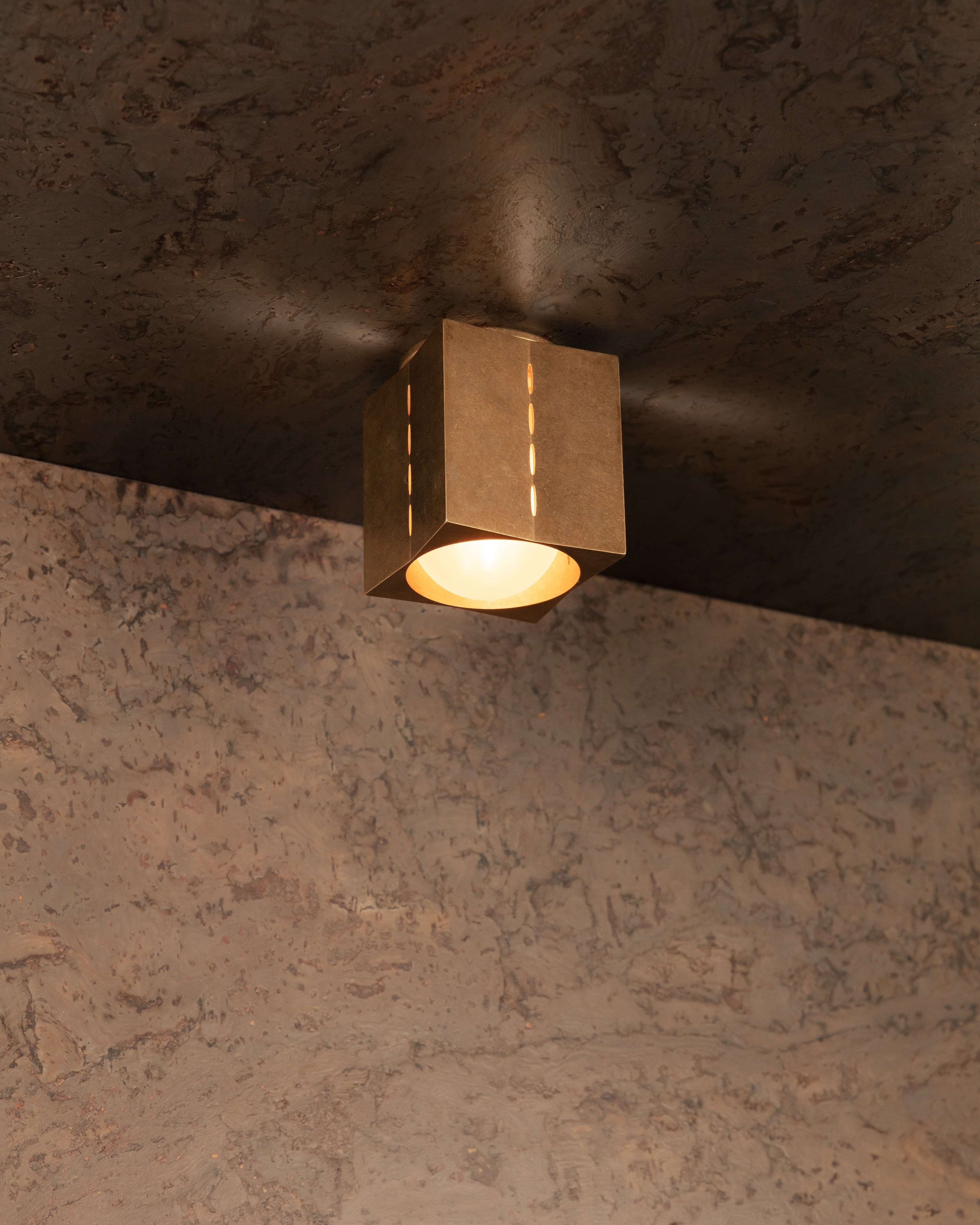 Ceiling light fixture on a textured ceiling and wall.