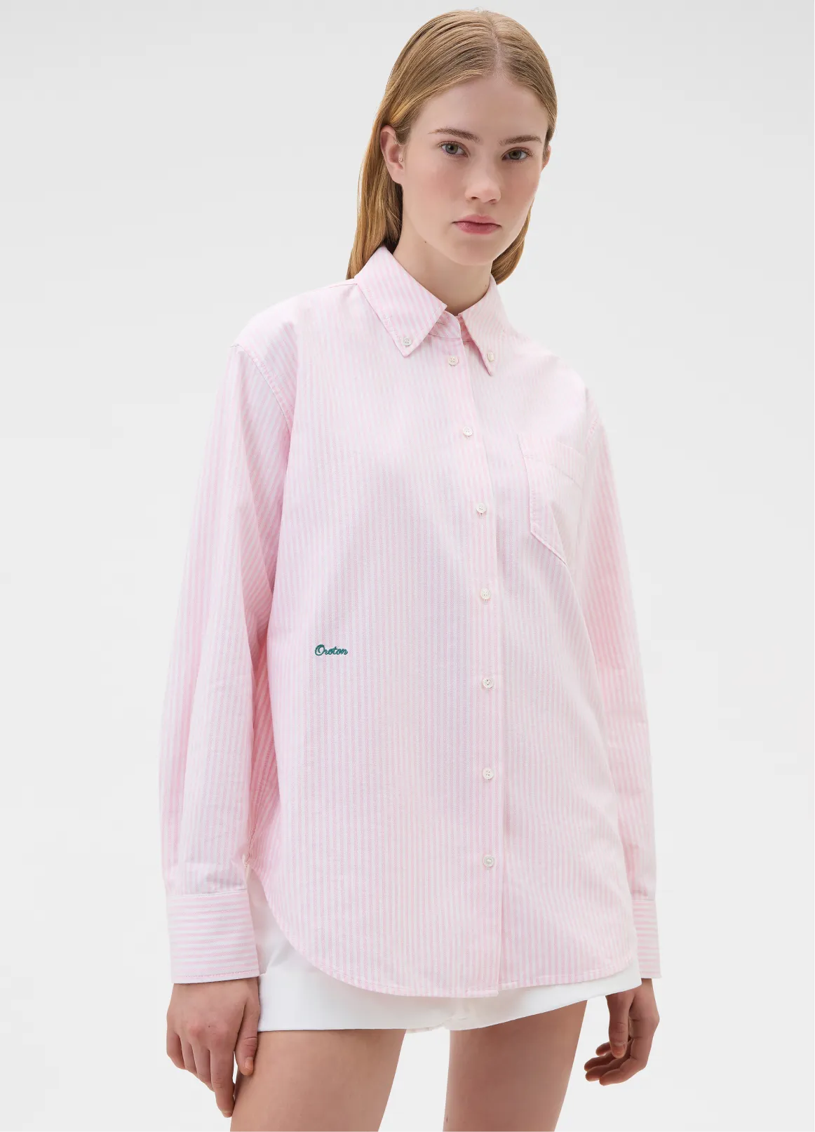 A woman wearing a pink button-up shirt with a collar.