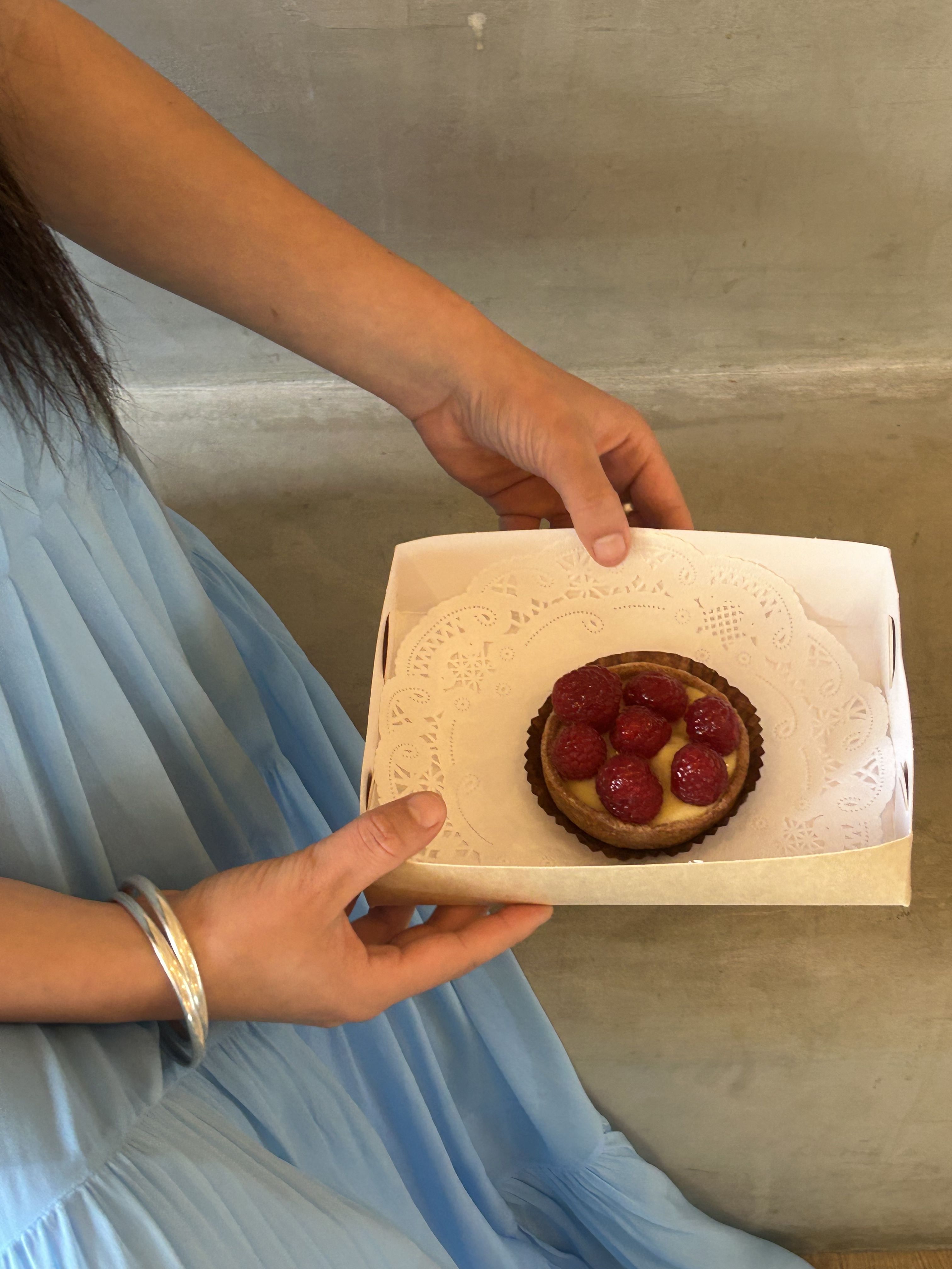 Frankie holds a pastry. She is wearing the Jena Cami Dress in Sky.