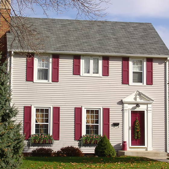 A colonial home with red shutters and copper and metal window boxes from Hooks and Lattice