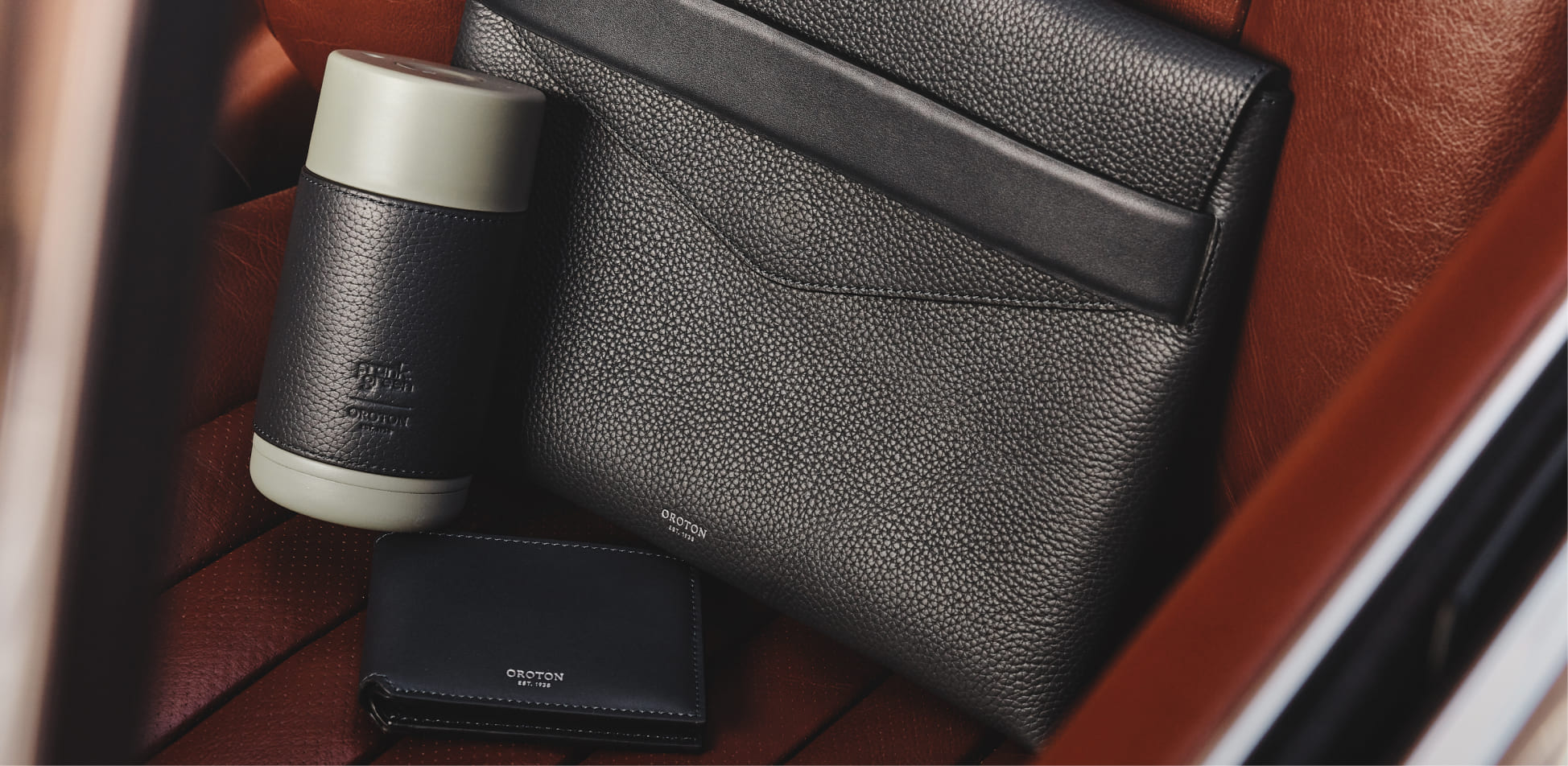 A black leather pouch, a cup, and a small case on brown leather.