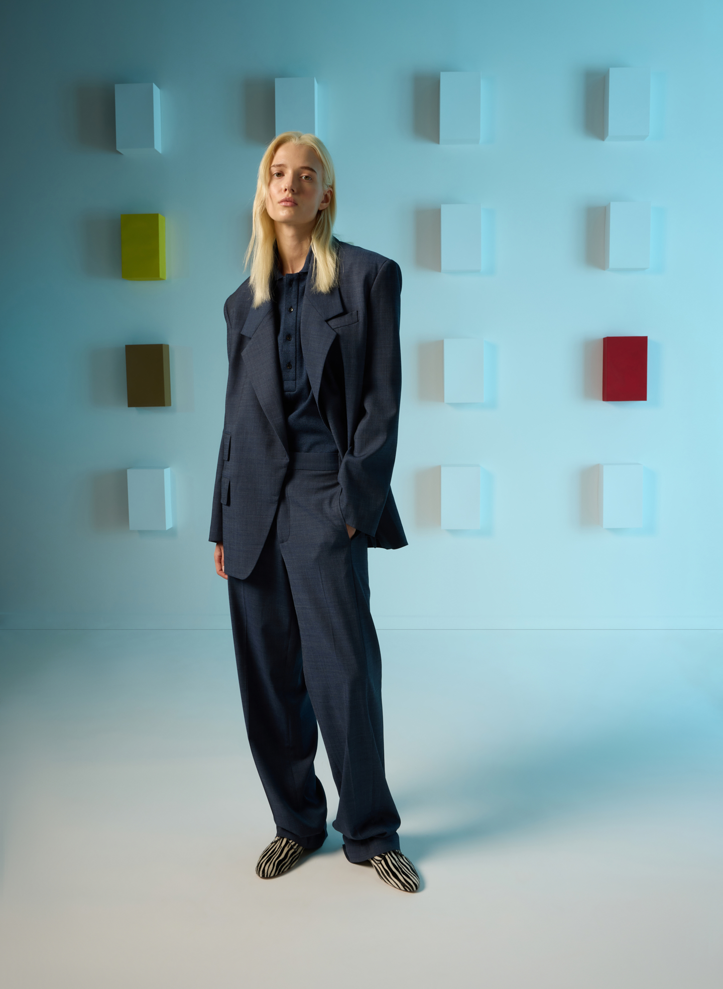 Person in oversized suit standing against colorful abstract background.