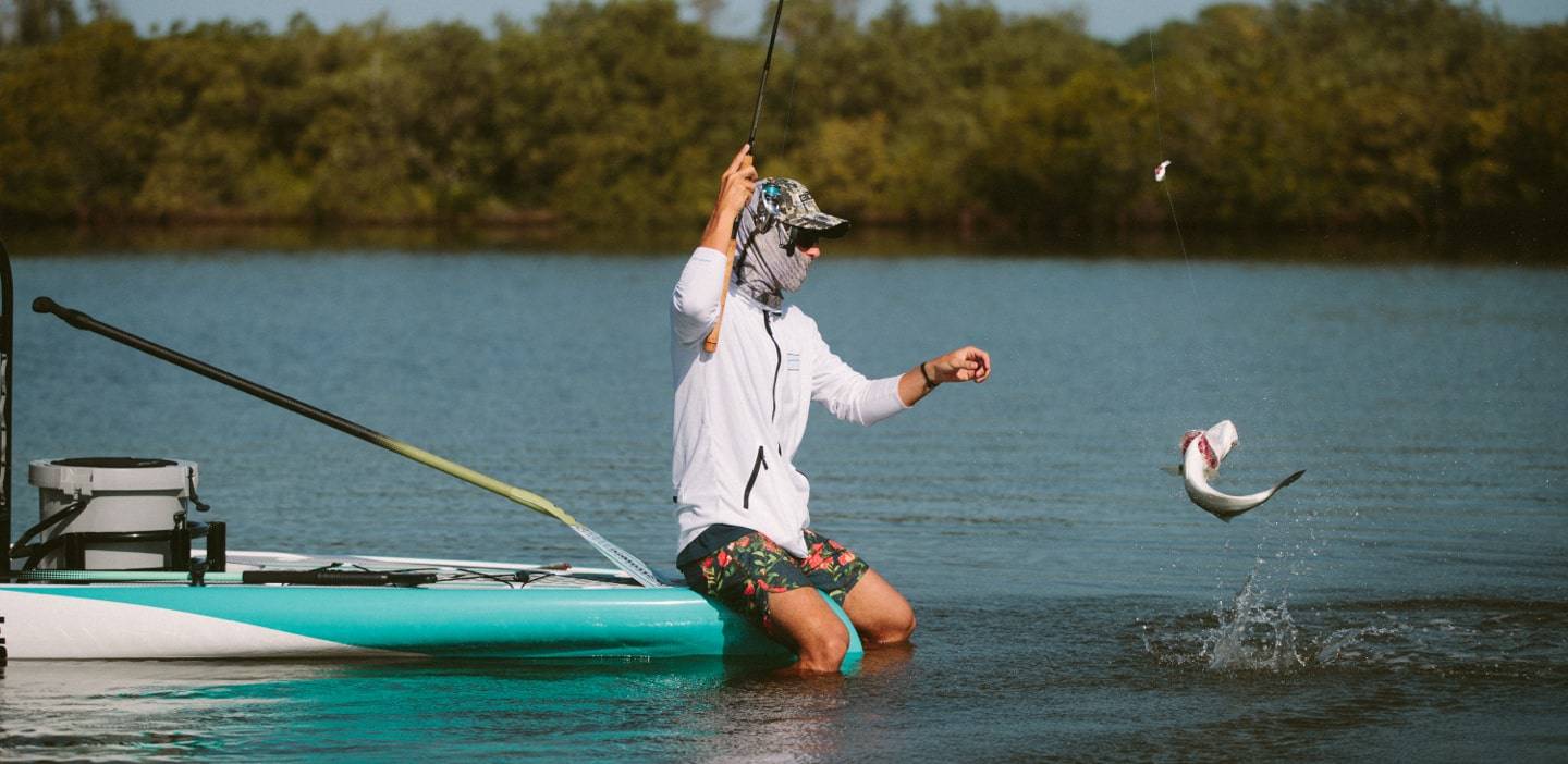 Man sitting on the nose of his Rover Gatorshell as he reels in a catch
