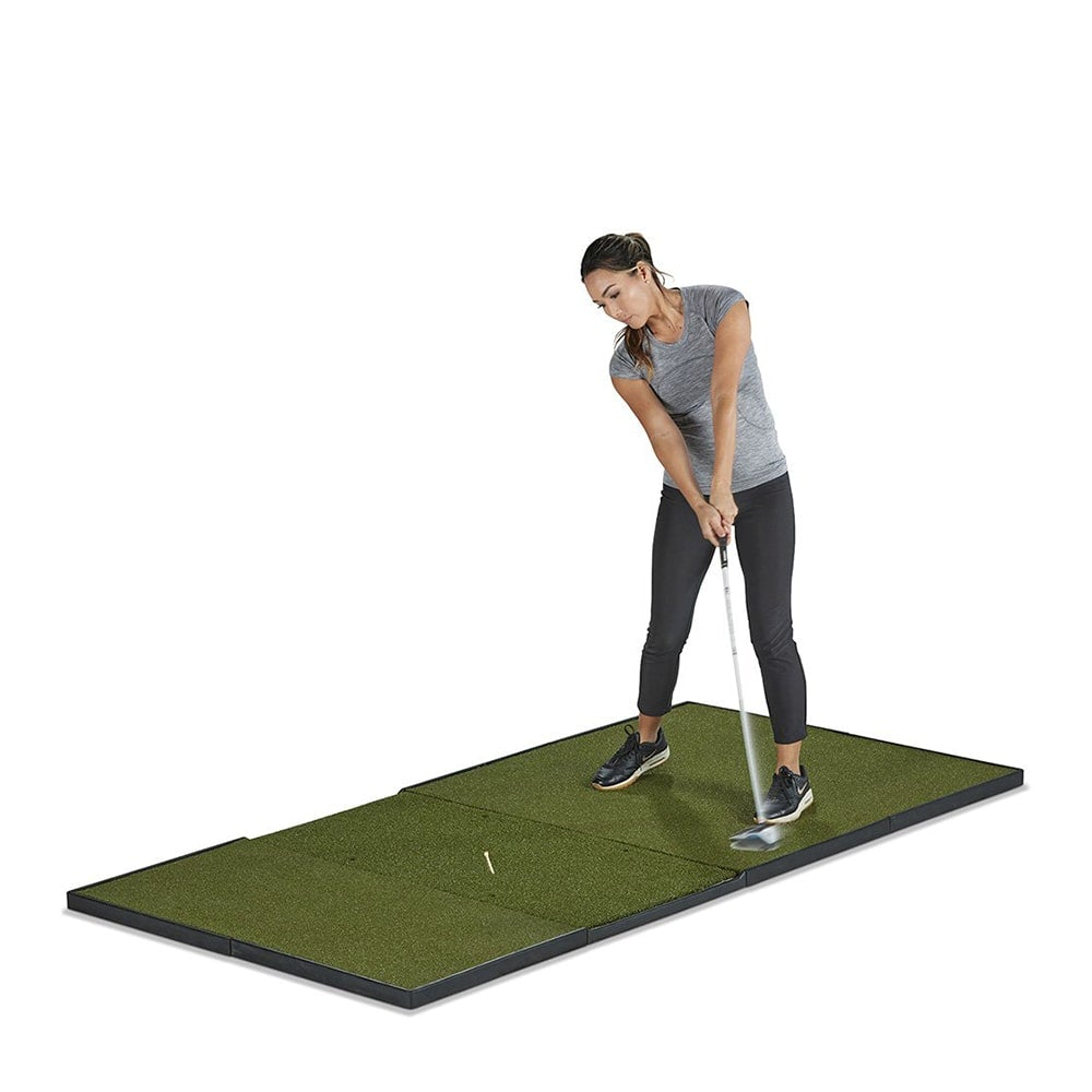 Woman hitting off a Fiberbuilt home golf studio mat