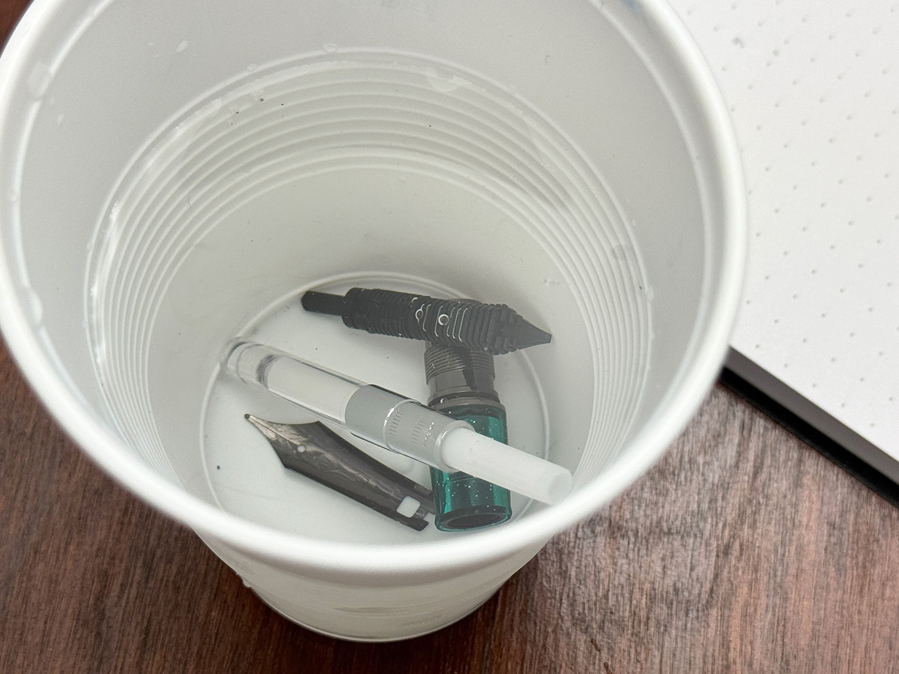 Sailor fountain pen parts soaking in a cup of water