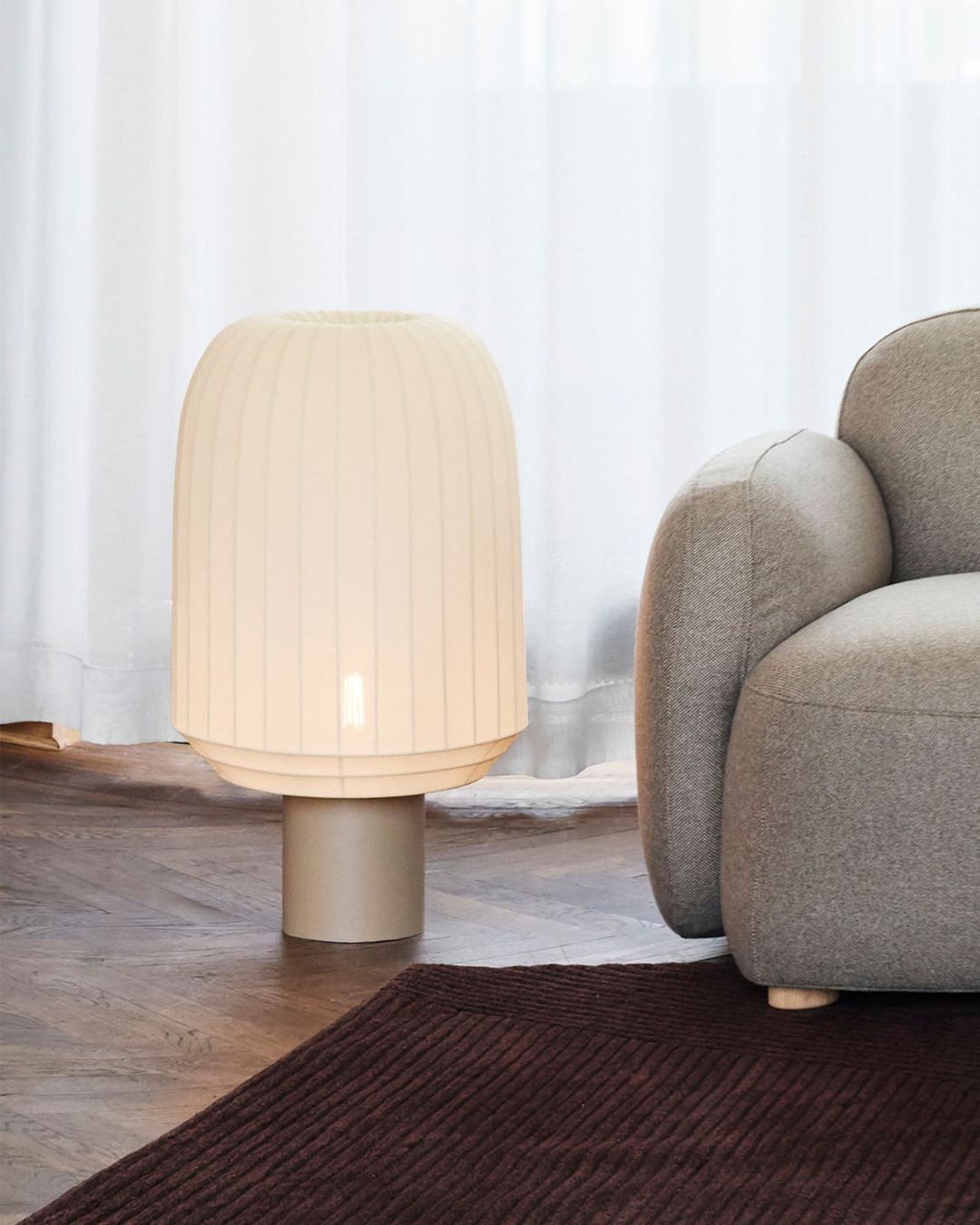 Knitted Stretched Fabric Floor Lamp next to a gray armchair in a room with white curtains.