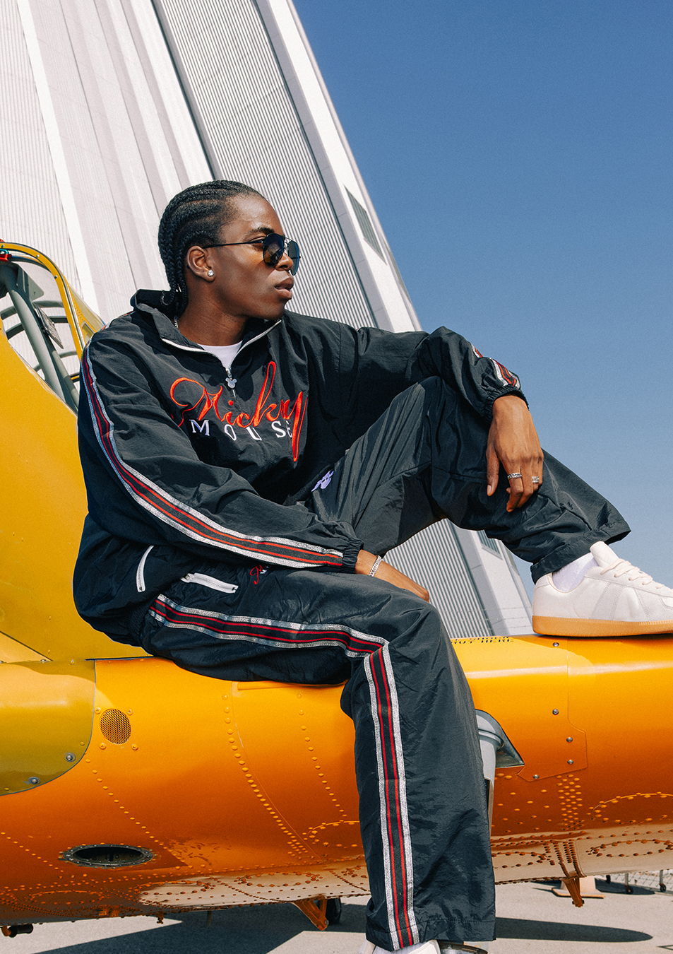 Person in a black tracksuit sitting on a yellow aircraft.