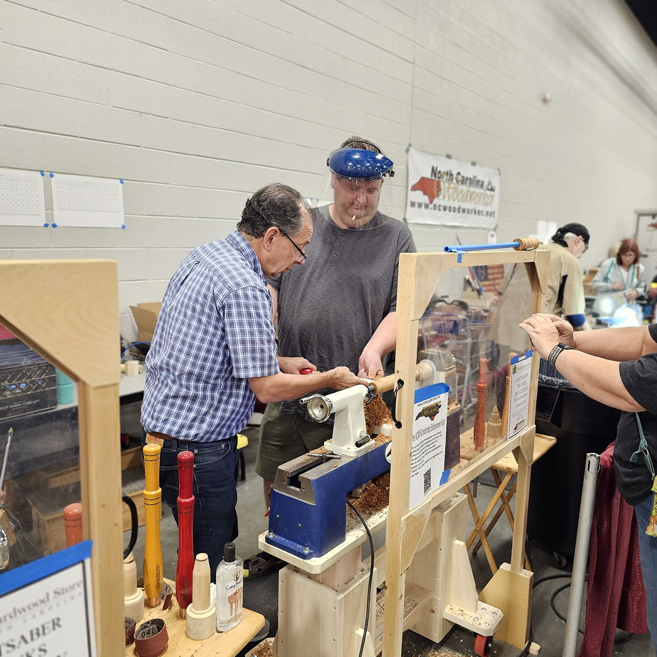 Two men working on woodturning at a craft fair.