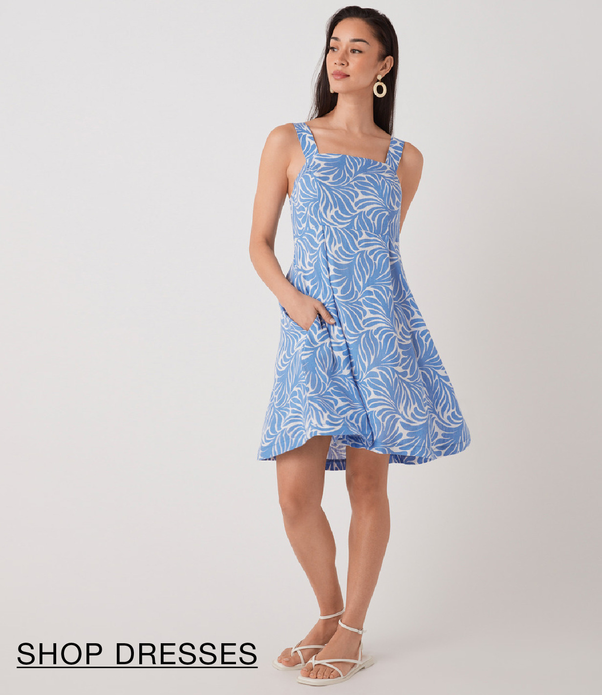 Model wearing a blue patterned dress with pockets.