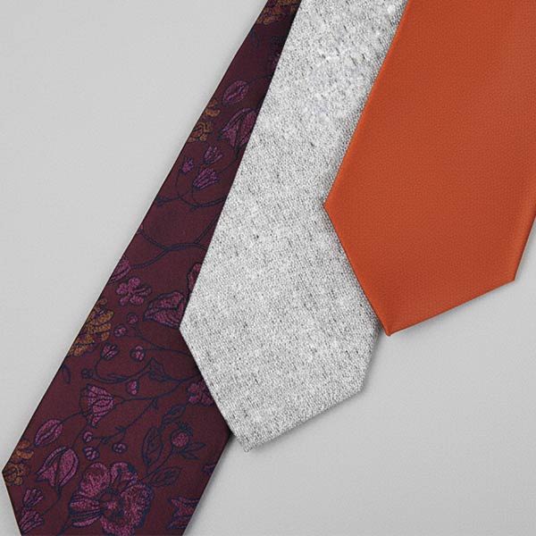 A burgundy floral, textured gray, and burnt orange solid tie
