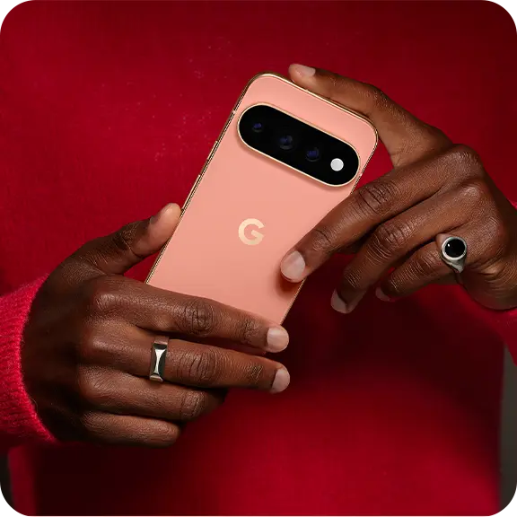 Person holding a peach-colored smartphone with a visible logo and camera.
